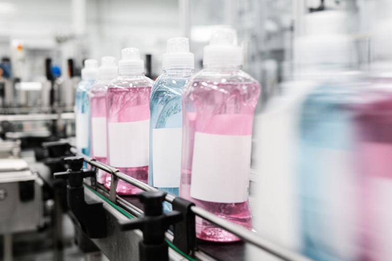 Detalle de una línea de envasado de productos de limpieza con botellas en movimiento
